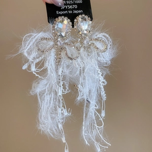 Detailed close-up of 925 silver bow earrings with crystals and white feather fringe