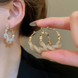 Close-up of gold mesh wrap hoop earrings with sparkling cubic zirconia inlay details
