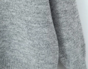 Gros plan du tissu d'un pull en maille grise montrant sa texture douce et sa qualité