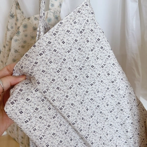 Gros plan sur un tissu en coton léger avec des motifs floraux bleu clair et violet foncé