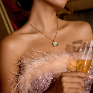 Vintage gold necklace with green window pendant worn by model in elegant party setting