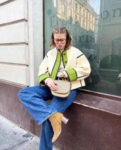 Detail of quilted off-white jacket with green contrast trim and brown button closure