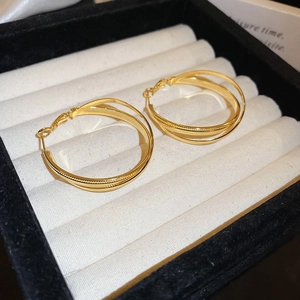 Close-up of golden double hoop earrings on white velvet jewelry display box