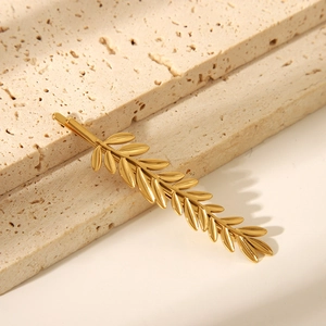 Dettaglio di un fermaglio per capelli in metallo dorato con venature fogliari su pietra