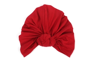 Detailed view of red knitted cotton turban hat featuring a central knot and soft pleats