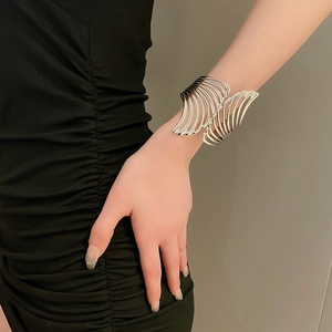 Close-up of polished silver open cuff bracelet with hollow wing and leaf feather pattern