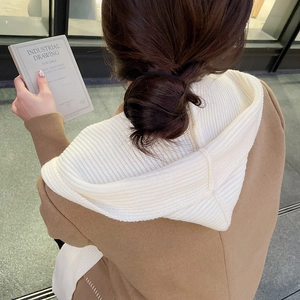 Detail view of the beige coat and white knitted hoodie back texture and drape