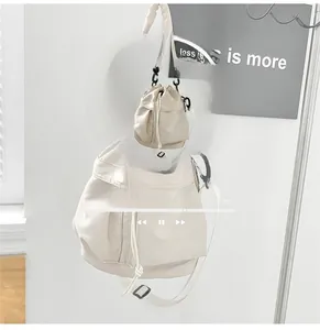 Detail view of off-white nylon bucket bag with drawstring closure and wide strap