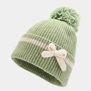 Detail of green knitted beanie with a large pom-pom and bow decoration for winter warmth