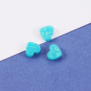 Close-up of blue heart-shaped resin charms with glitter fragments for DIY jewelry