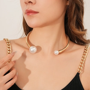 Detail shot of a gold open collar necklace with two white pearls on a female model