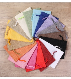 Flat lay of colorful linen drawstring bags in various shades on light wood background