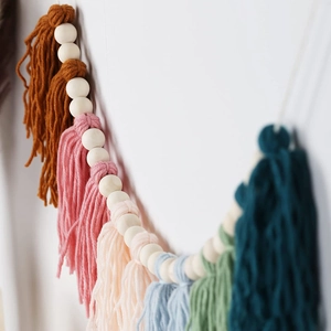 Close-up of bohemian wood bead garland with colorful cotton tassels for home decor