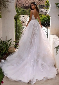 Detailed back view of backless white wedding dress with lace embroidery and long train