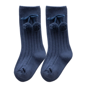 Navy blue knee-high baby socks with vertical rib knit and decorative cherry pom-poms