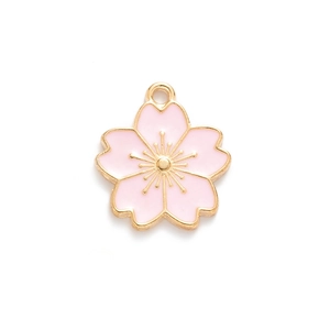 Macro shot of pink enamel cherry blossom charm with gold-plated base and loop