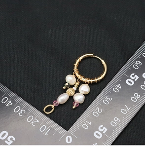 Detailed view of baroque pearl drop earrings with measurement scale on black background