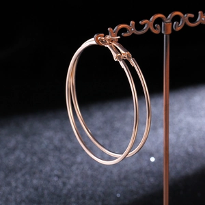 Detail view of large rose gold hoop earrings featuring polished surface and mirror finish