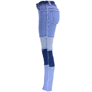 Dettaglio di jeans patchwork a vita alta in denim blu con cuciture a taglio vivo
