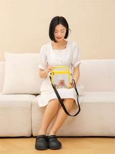 Macro detail of clear PVC crossbody bag with yellow trim showing zipper and storage space
