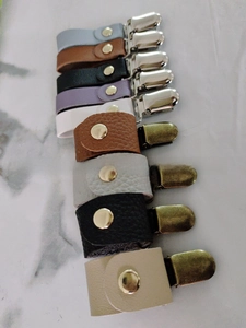 Makro-Detail von bunten Leder-Hutclips mit robusten Metallbeschlägen auf Marmor