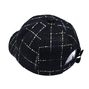 Close-up of black tweed baseball cap with gold plaid pattern and metal adjustment buckle