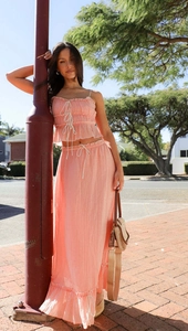 Detail of peach pink two-piece set featuring a drawstring top and pleated maxi skirt fabric