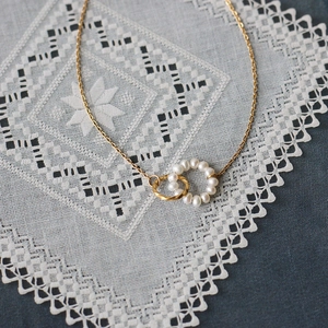Elegant gold titanium steel necklace featuring dual rings with pearls and twisted metal