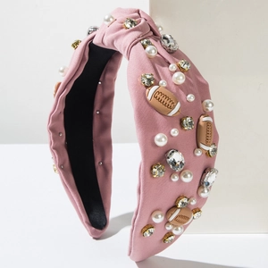 Pink knotted headband with rhinestones, pearls and football charms on a white background