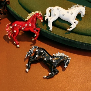 Detailed macro of vintage horse brooches in red, white, and black enamel with rhinestones