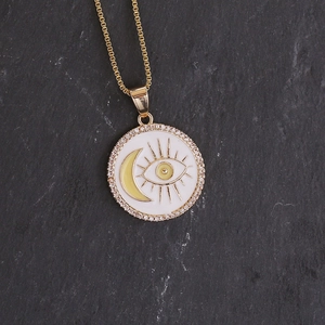 Macro shot of gold necklace with crescent moon and eye pendant set on grey stone texture