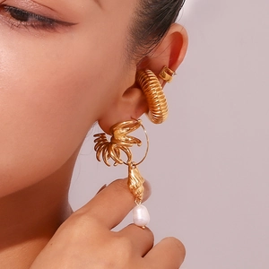Detail of 18K gold plated hoop earrings with shell and freshwater pearl on model ear