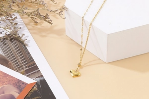 Golden heart pendant necklace with fine chain displayed on a minimalist artistic background