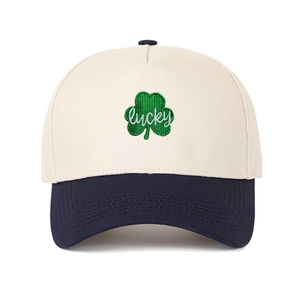 Close-up of green clover embroidery and lucky script on a beige cotton trucker hat