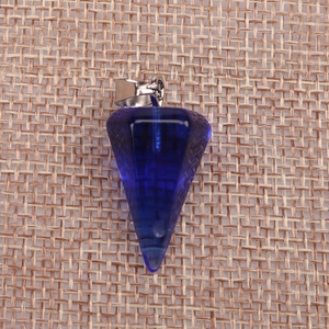 Close-up of a faceted deep blue crystal pendulum pendant on a natural jute background