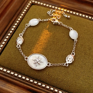 Detailed shot of silver starburst bracelet with oval opal stone on green velvet