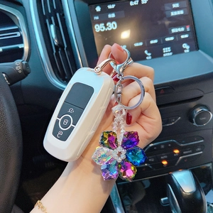 Close-up of white car key cover with colorful crystal snowflake keychain in a car