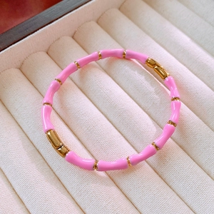 Dettaglio del bracciale stile bambù smaltato rosa con maglie dorate su scatola