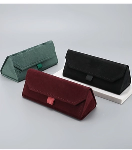 Close-up of velvet triangular foldable eyewear cases in green, black, and burgundy colors