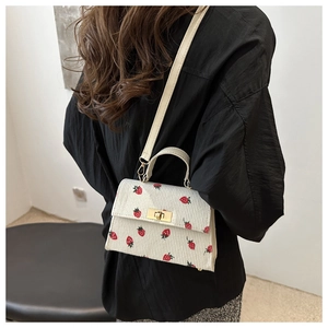 Model wearing a white corduroy crossbody bag featuring cute red strawberry patterns