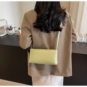Detailed view of a light green rectangular shoulder bag styled on a coffee shop counter
