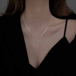 Dettaglio della collana lunga a Y in argento con nappe e perle su modella