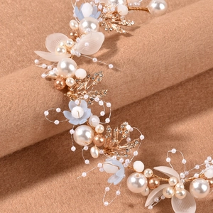 Macro detail of handmade bridal headband with gold leaves, pearls and blue flowers