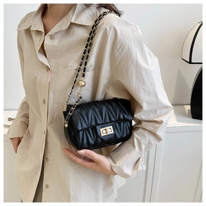 Close-up of black quilted crossbody bag featuring a gold clasp and woven chain strap