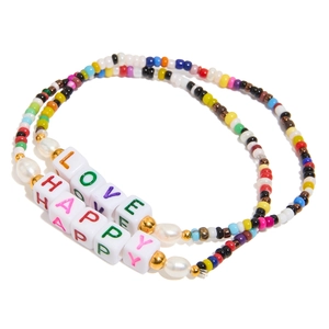 Detail of colorful beaded bracelets with white LOVE and HAPPY letter cubes and pearls