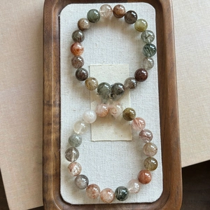 Close-up of multicolored rutilated quartz crystal beads on a textured wooden tray