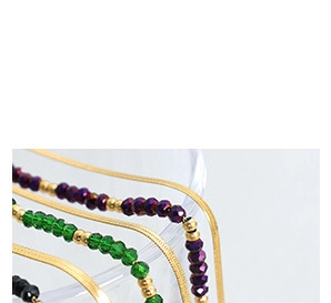 Dettaglio macro di collane con perline colorate, catene a serpente oro e zirconi