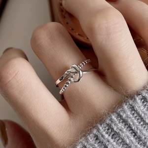 Detail shot of a silver knot double-layer ring on a finger with a cozy knit sweater