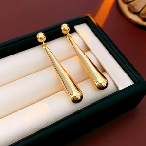 Close-up of golden teardrop earrings on a white velvet cushion inside a jewelry box