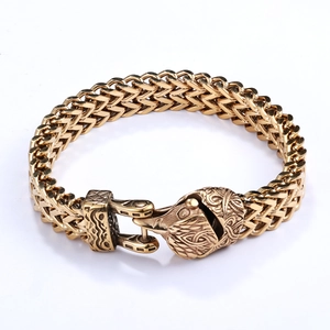 Close-up of vintage gold stainless steel woven chain bracelet with wolf head clasp detail